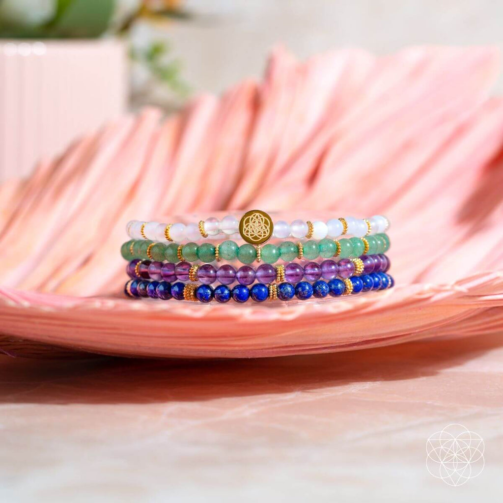 Stack of colorful beaded bracelets on a pink leaf