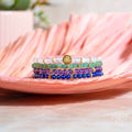 Stack of colorful beaded bracelets on a pink leaf