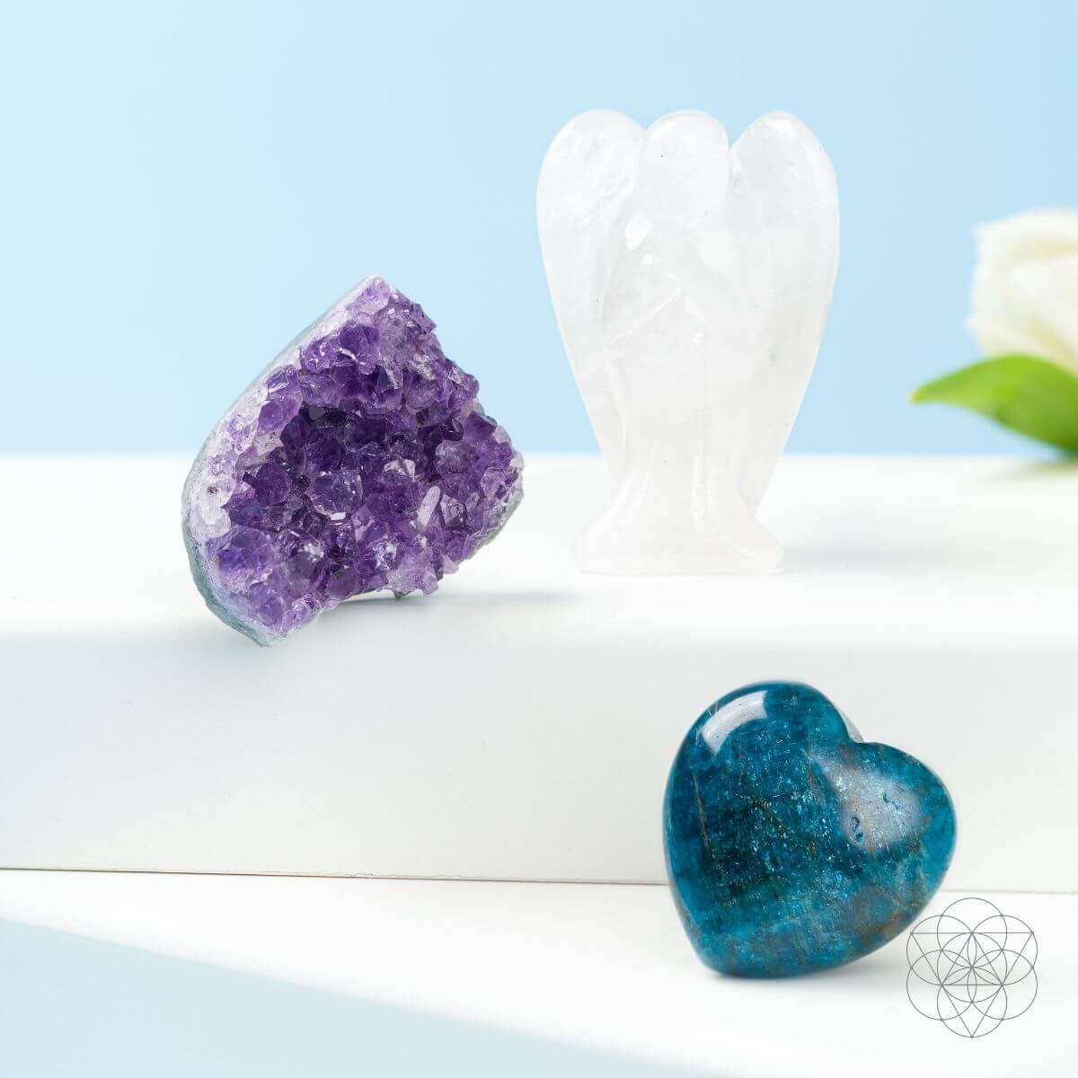 Crystal heart, amethyst crystal, and white sculpture on a light blue background