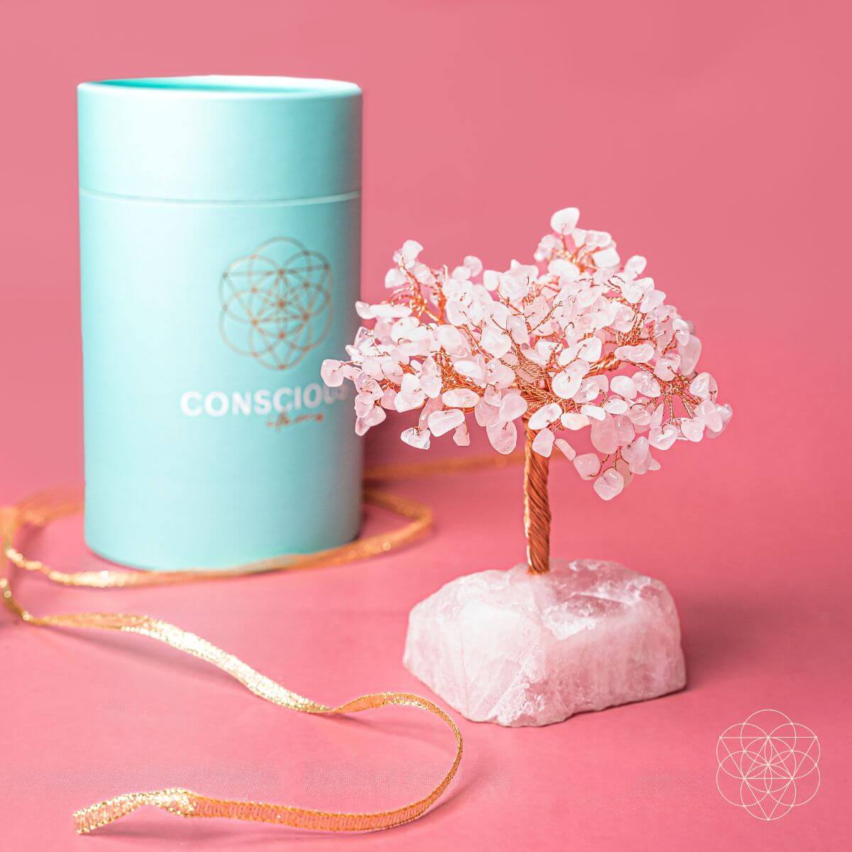 Decorative crystal tree on a pink background with a teal cylindrical container labeled 'Conscious'.