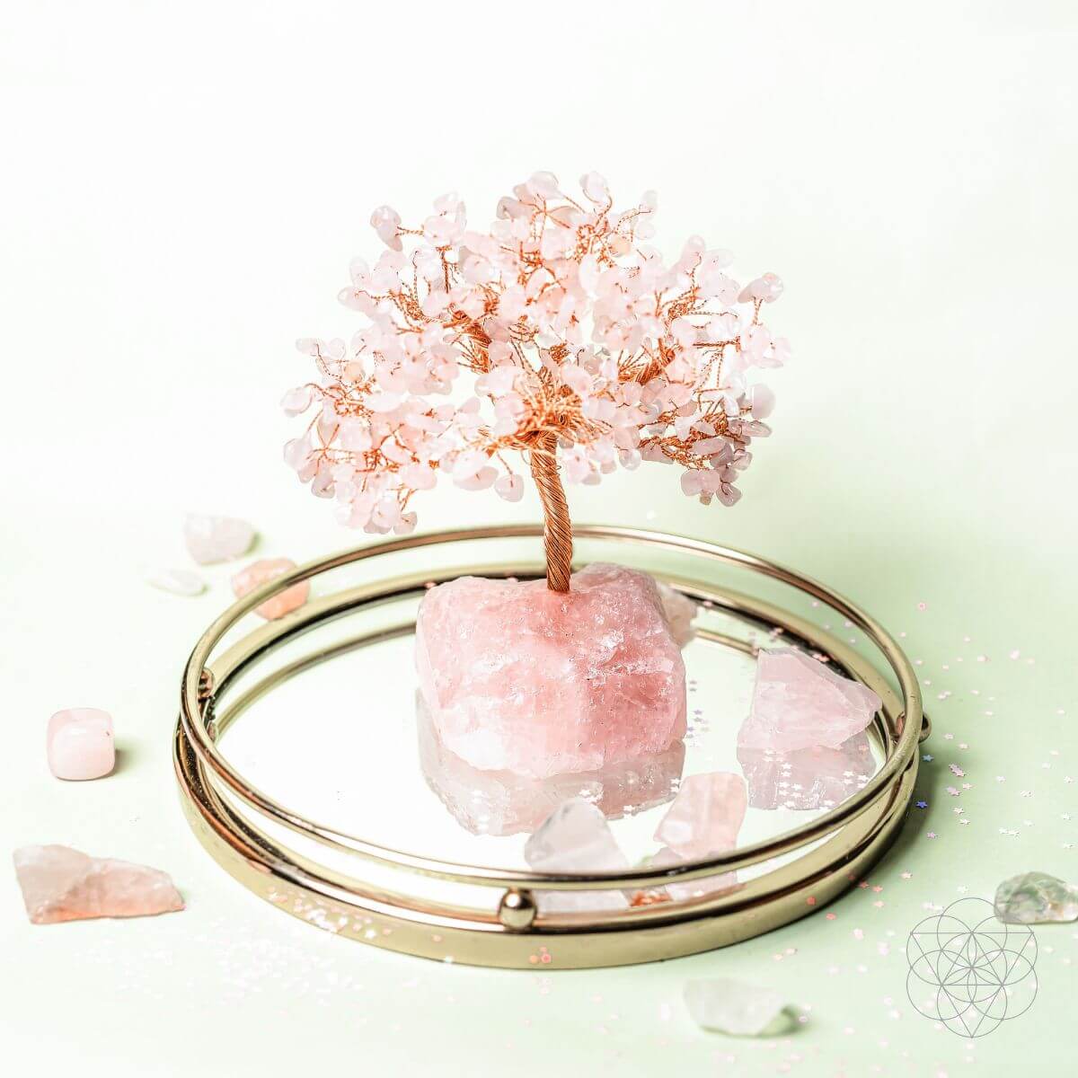 Decorative compact mirror with pink crystal and tree on a light green background