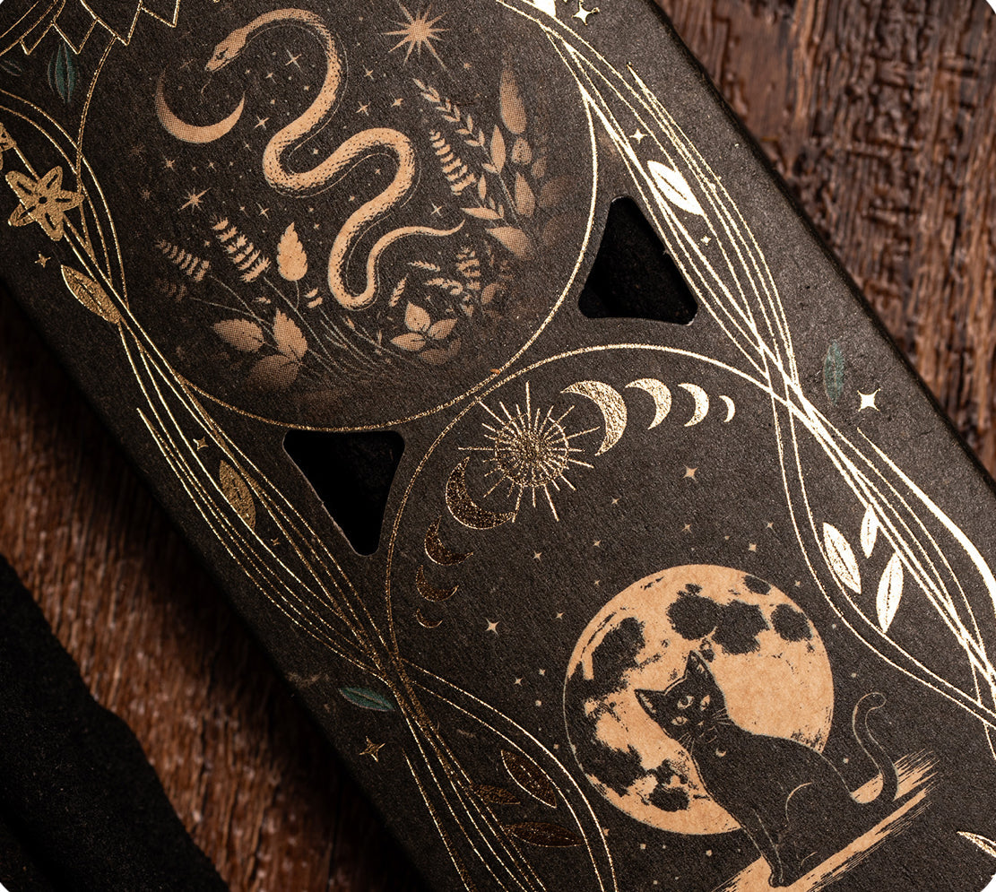 Decorative phone case with celestial design featuring a snake, moon, and cat on a textured surface.