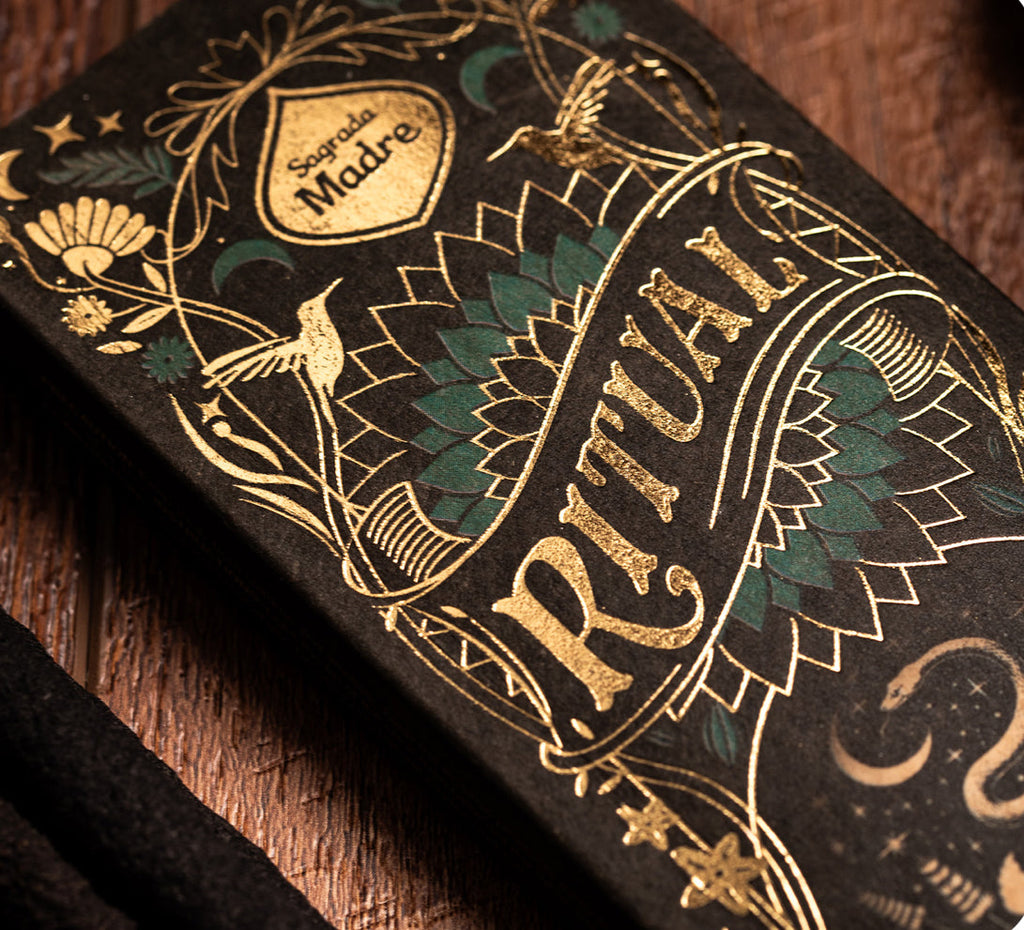 Decorative product packaging with gold and green designs on a wooden surface