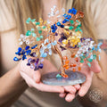 Colorful crystal tree held by hands with a blurred background