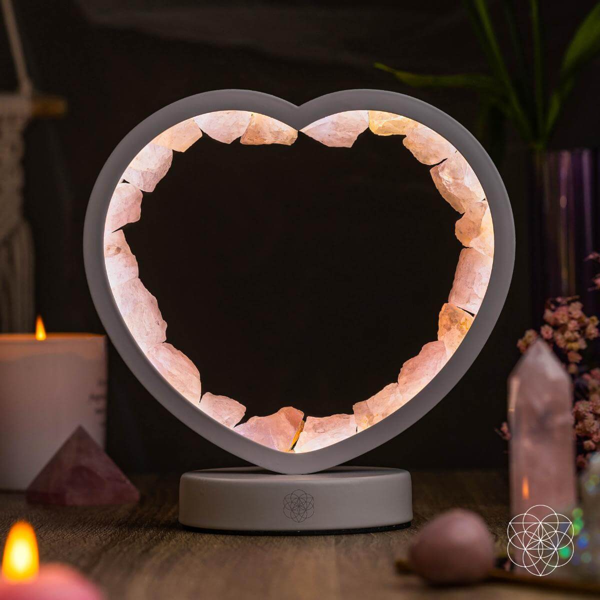 Heart-shaped salt lamp on a dark background with candles and crystals.