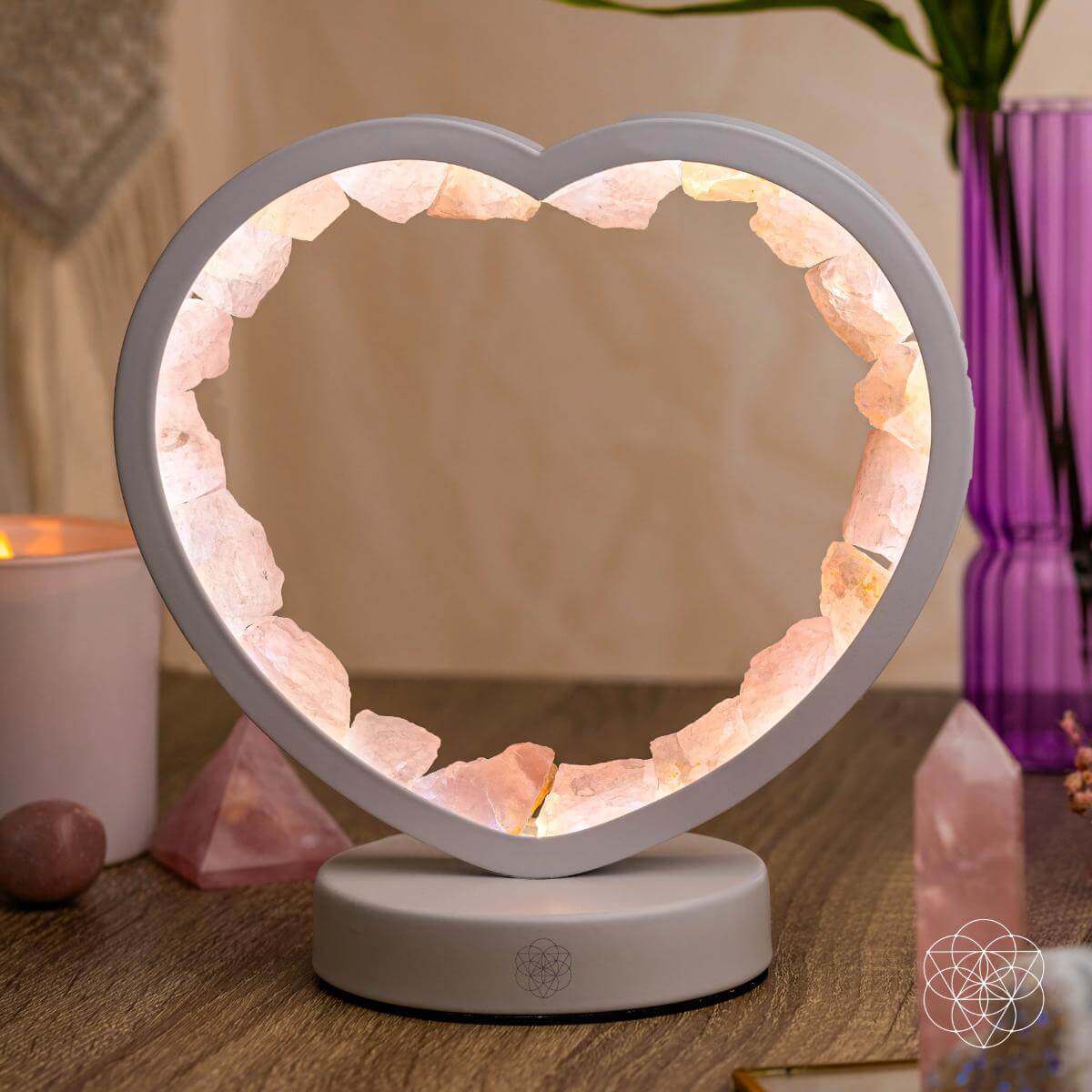 Heart-shaped salt lamp on a wooden surface with candles and crystals in the background