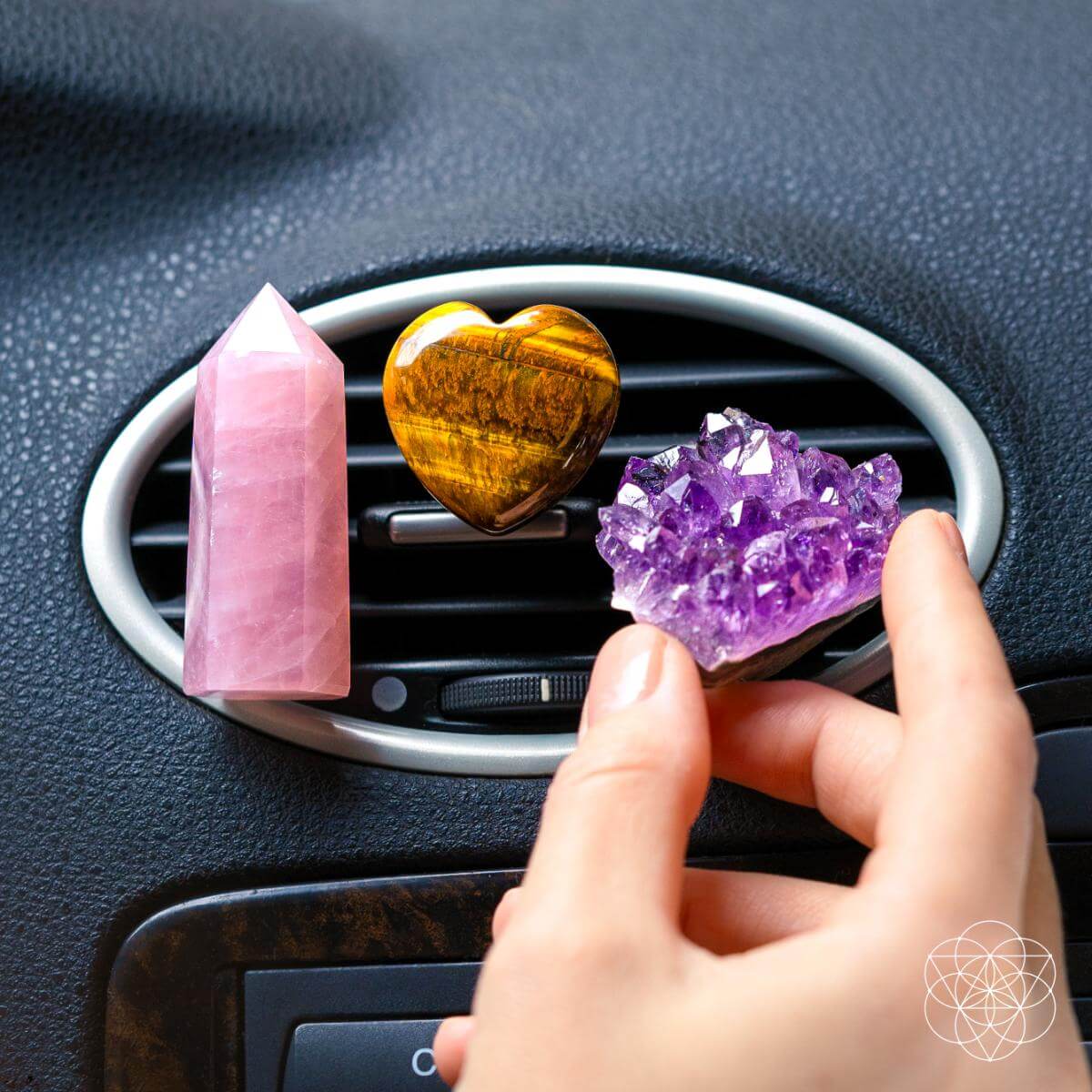 Decorative crystals in a car air vent with a hand reaching towards them