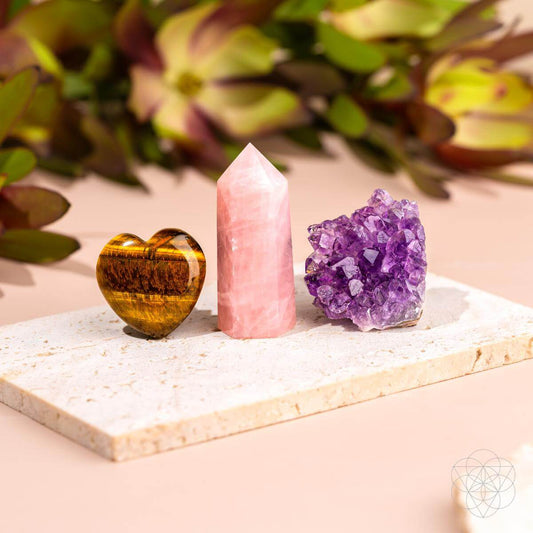 Three crystals on a white stone surface with a blurred natural background