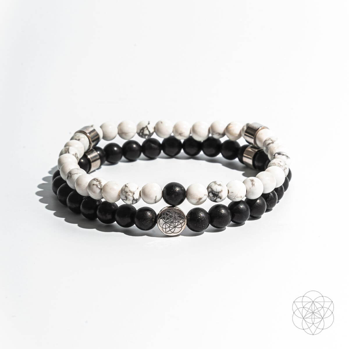 Set of three beaded bracelets with black, white, and silver beads on a light gray background