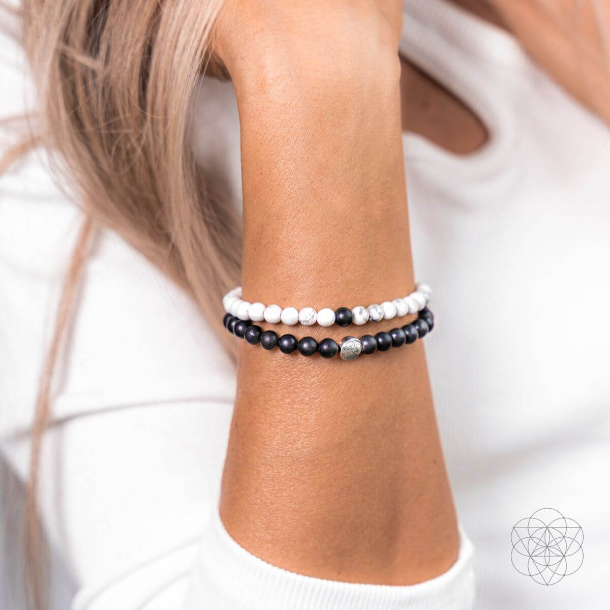 Two beaded bracelets on a wrist against a white background