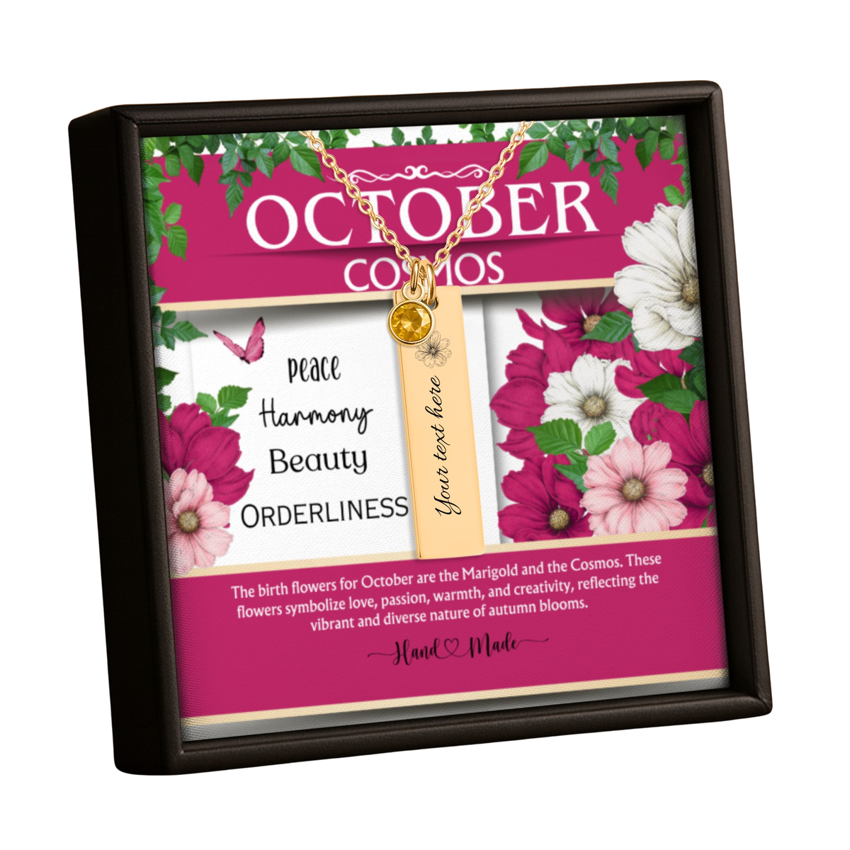 A framed October Cosmos themed keepsake box containing a gold necklace with a round charm and a vertical tag that reads 'Your text here.' The insert card features pink, white, and green floral artwork with the words 'Peace, Harmony, Beauty, Orderliness' and a 'Hand Made' logo.