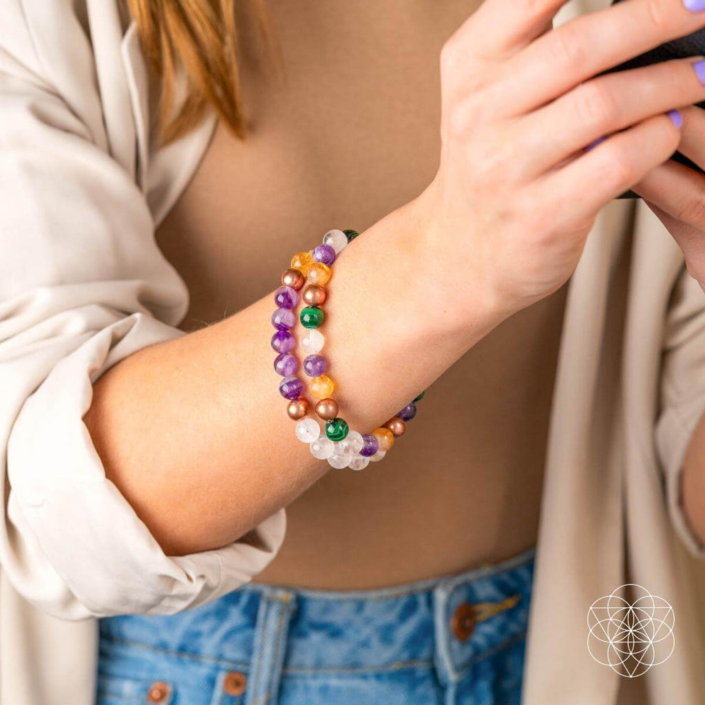 Person wearing a colorful beaded bracelet on a neutral background
