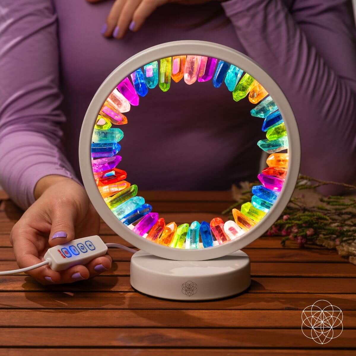 Colorful LED ring light on a wooden surface with a person holding it.