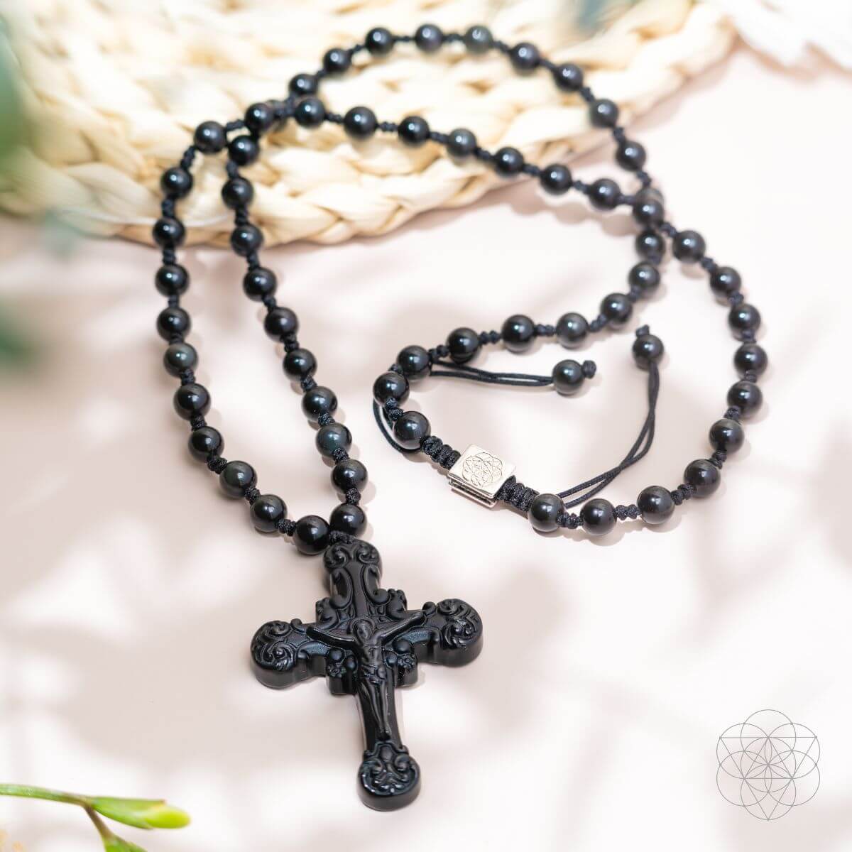 Black beaded necklace with a detailed cross pendant on a light background