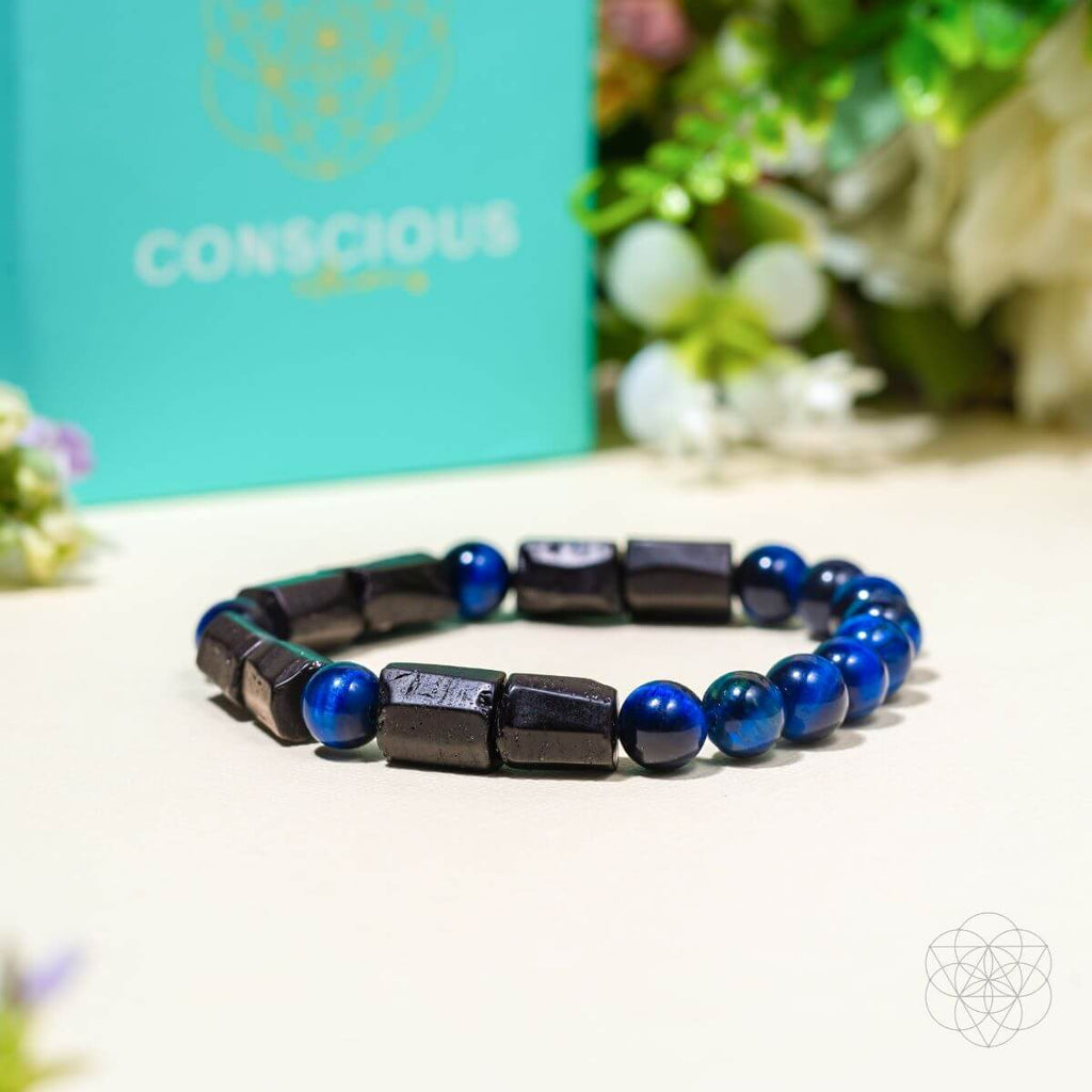 Black and blue beaded bracelet on a white surface with a 'Conscious' branded box in the background.