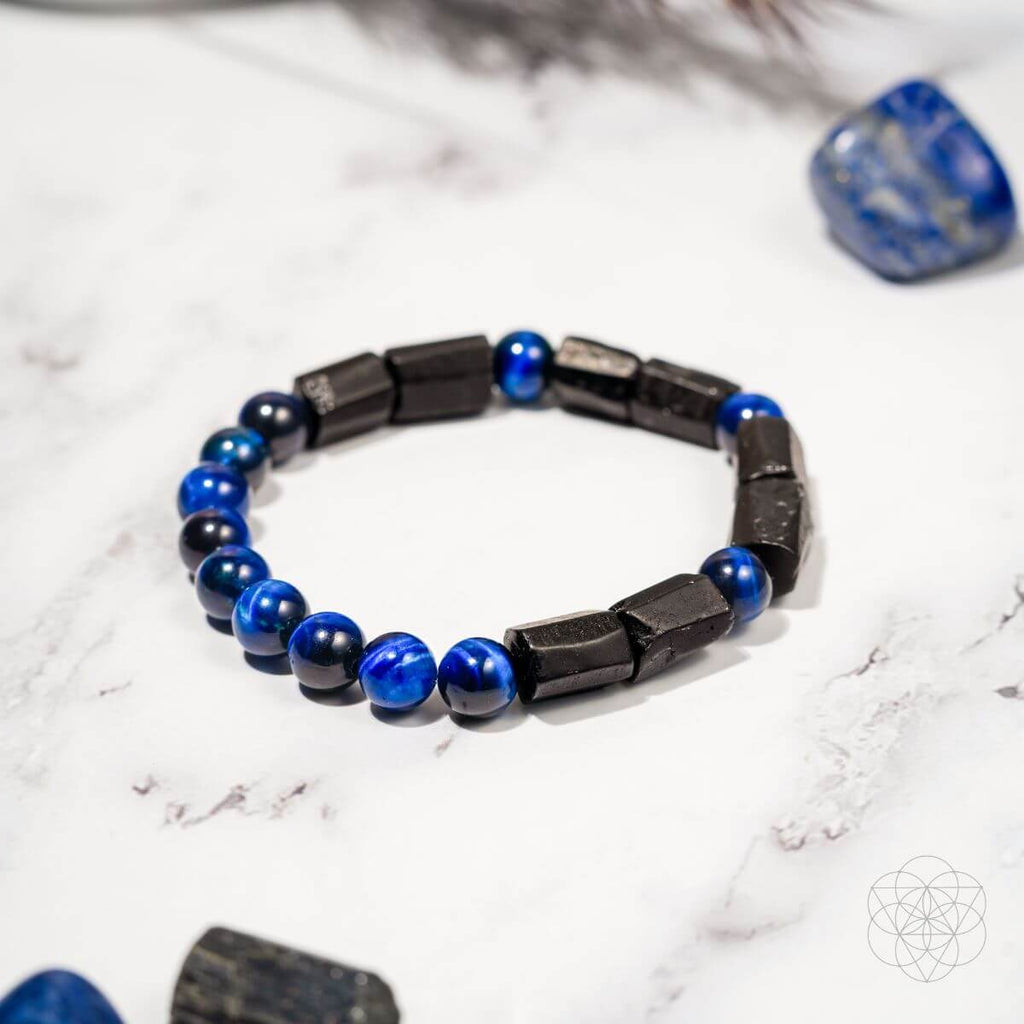 Bracelet with blue and black beads on a white marble surface