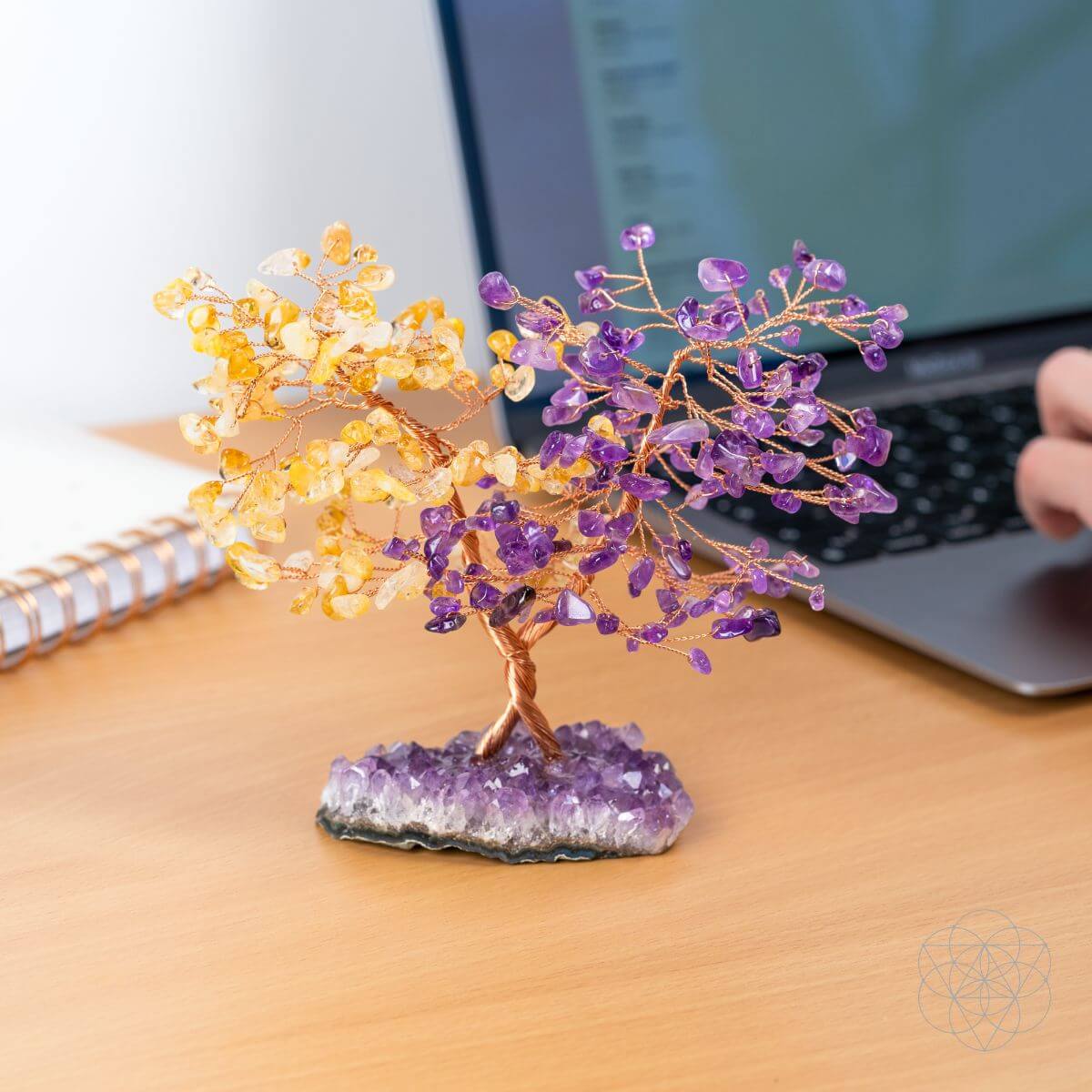 Decorative crystal tree on a desk with a laptop in the background