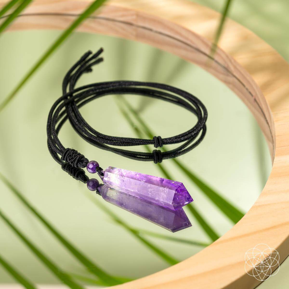 Black cord bracelet with purple crystal pendant on a natural background