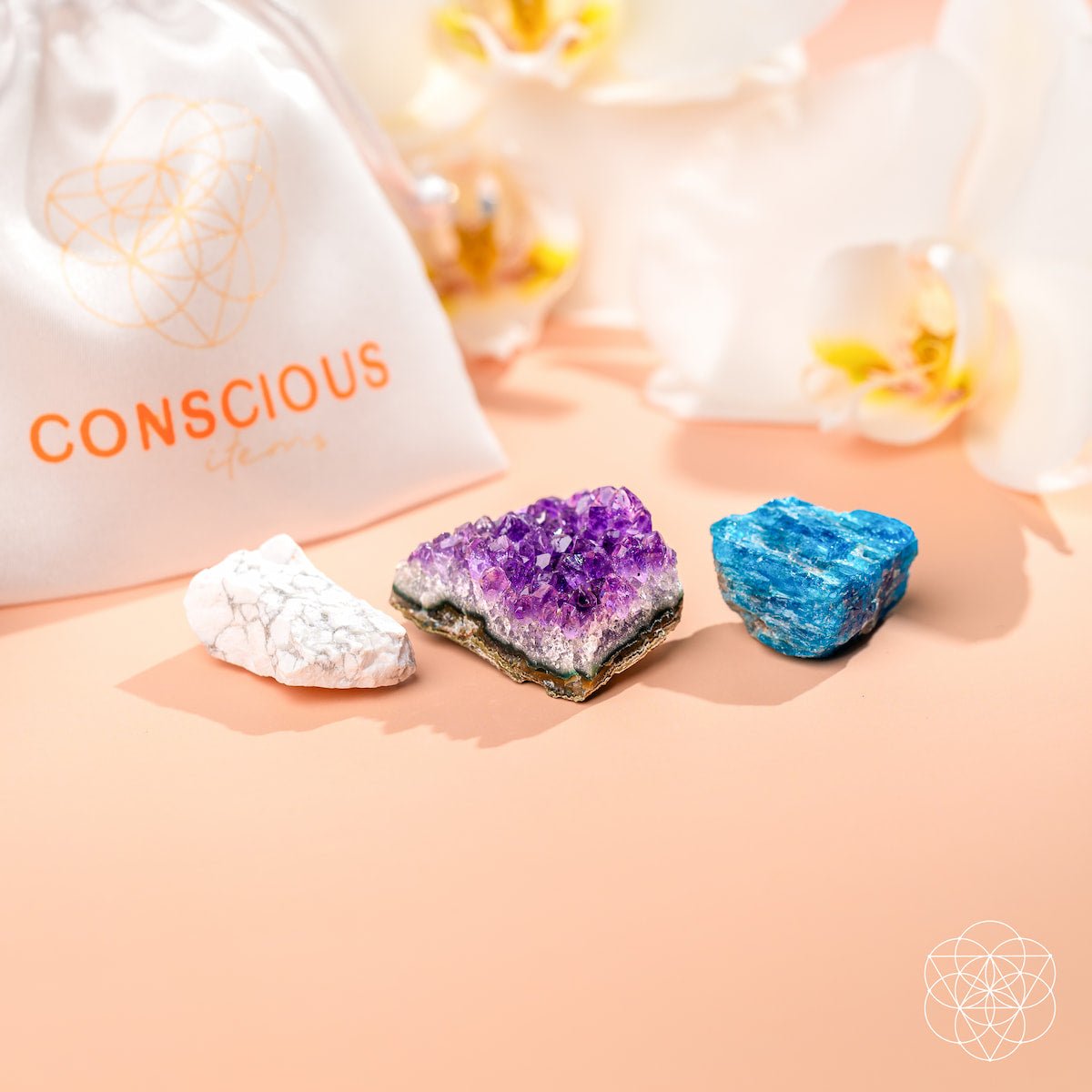 Three crystals on a pink surface with a 'Conscious' branded bag in the background.