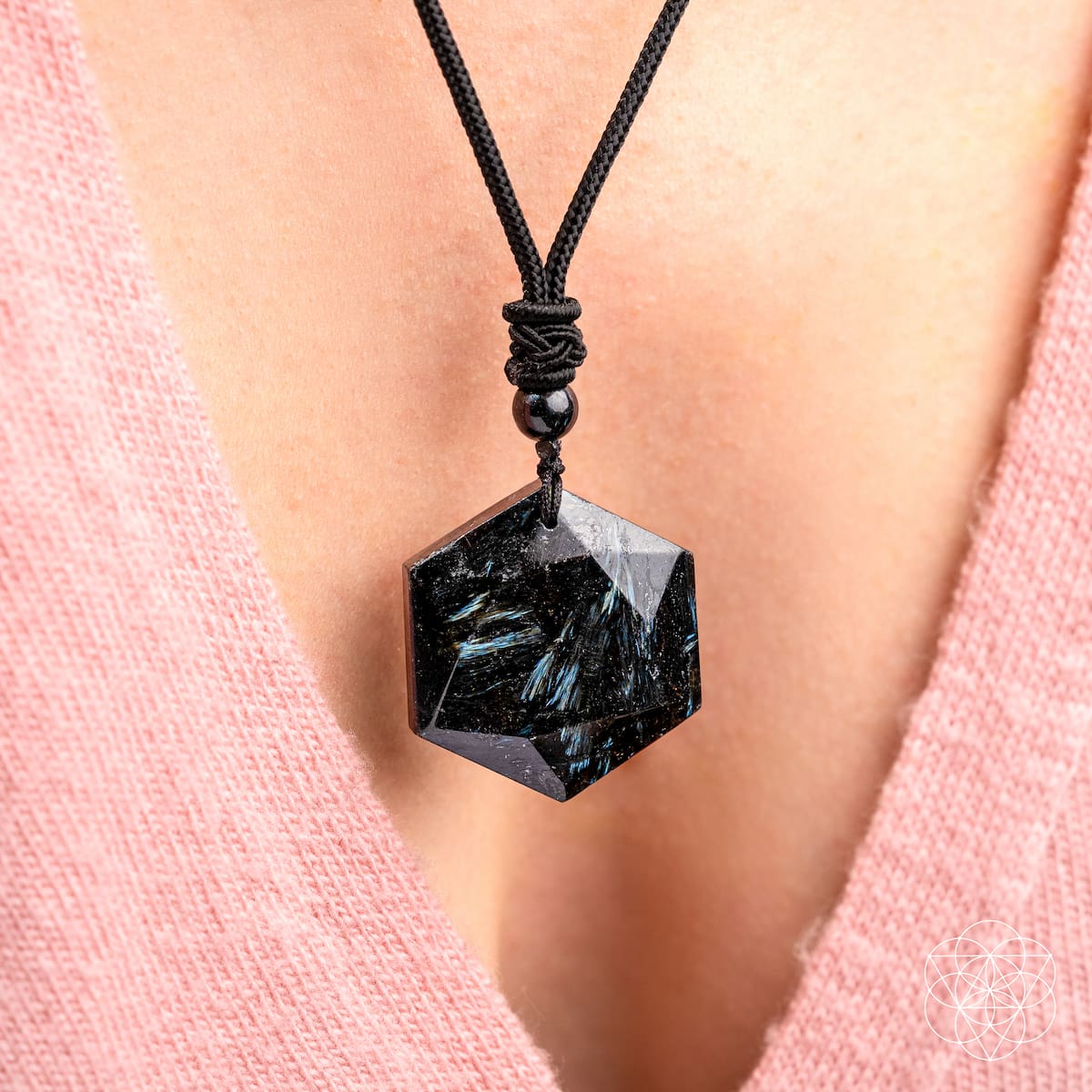 Black stone pendant necklace on a person wearing a pink garment
