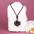 Necklace with a black pendant on a white stone with a pink background