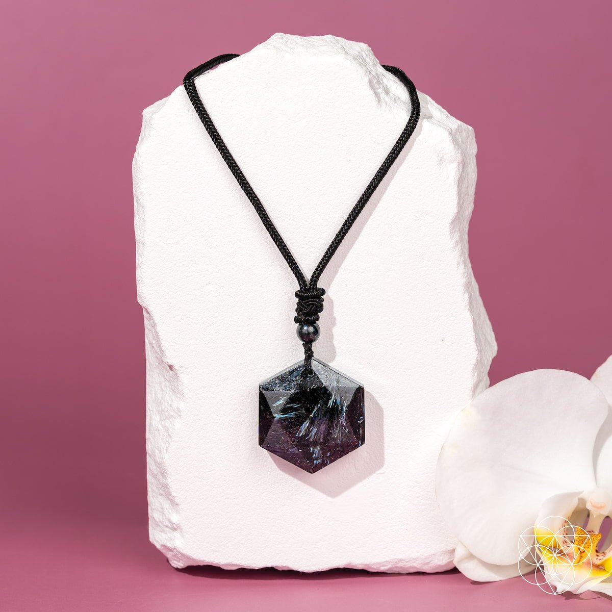 Necklace with a black pendant on a white stone with a pink background