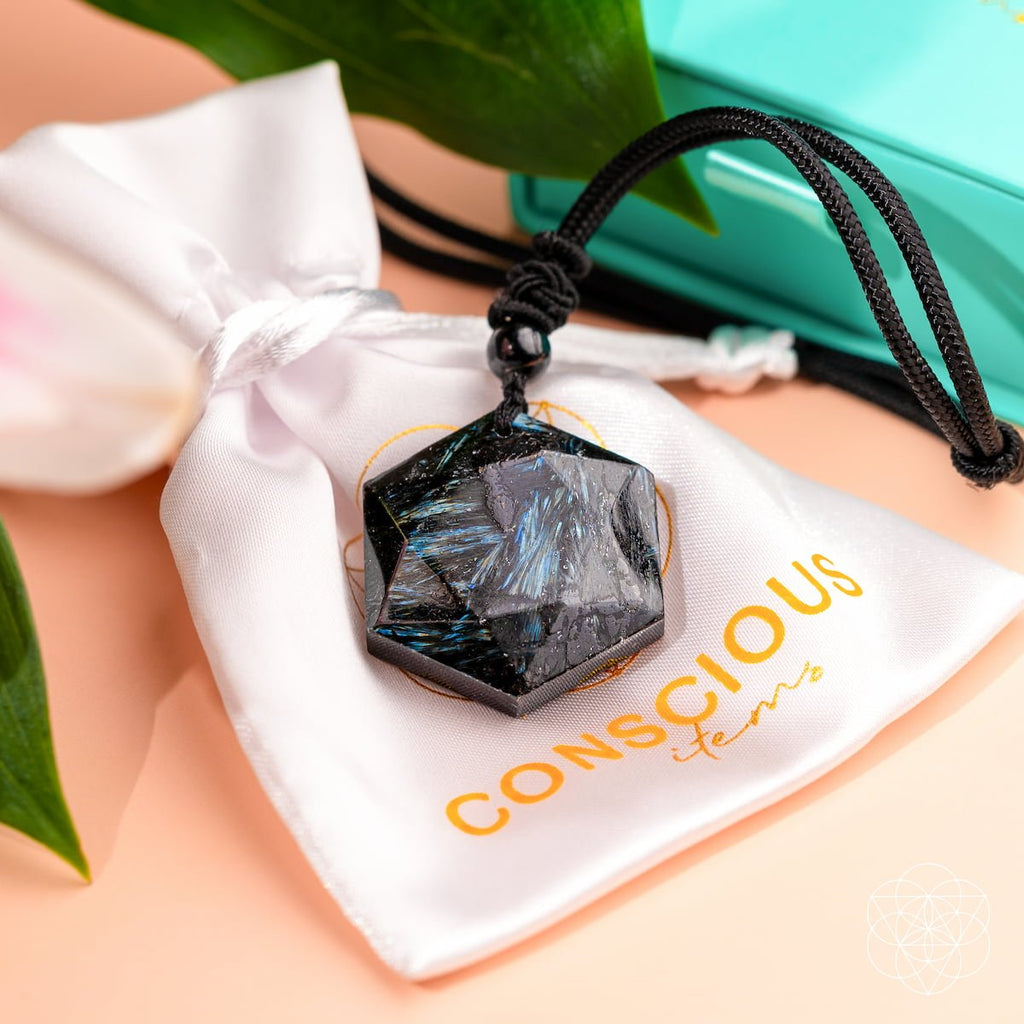 Necklace with a black stone pendant on a white drawstring bag with 'Conscious' branding.