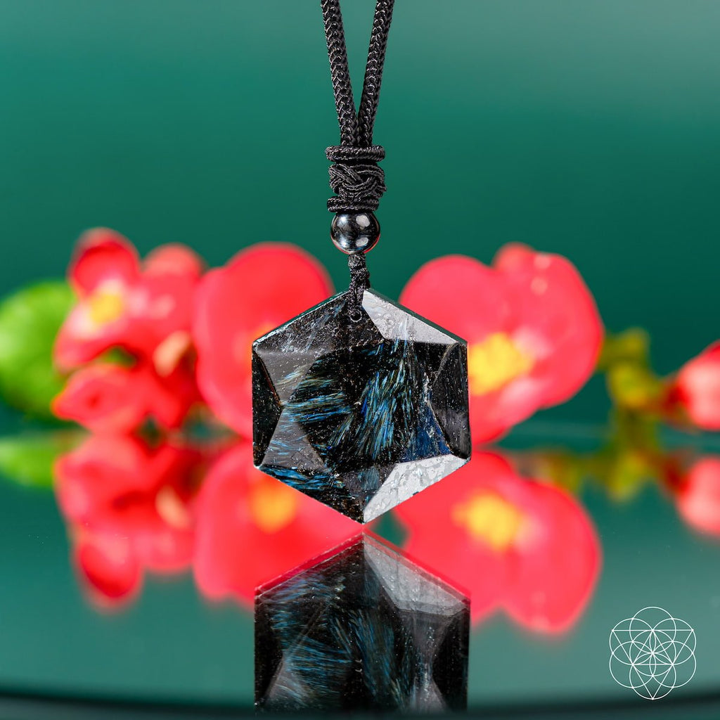 Hexagonal crystal pendant on a black cord with a blurred floral background