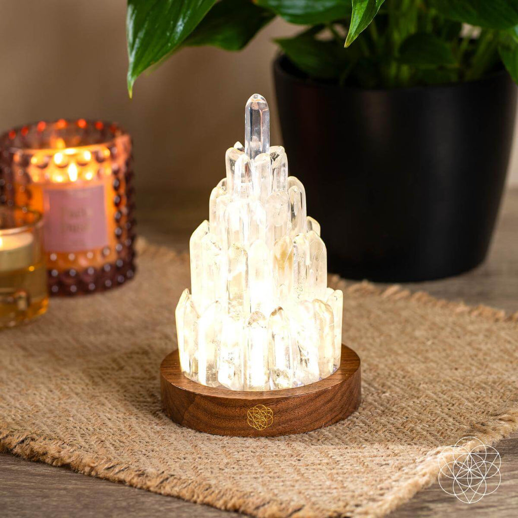 Crystal lamp on a wooden base with candles and a plant in the background