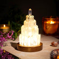 Crystal lamp with wooden base on a table with candles and flowers in the background