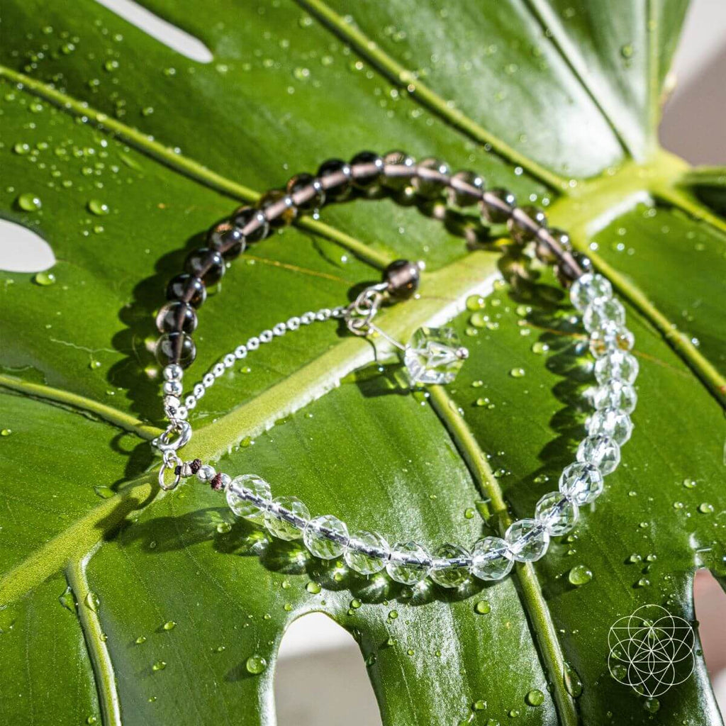 Two beaded bracelets on a green leaf with water droplets