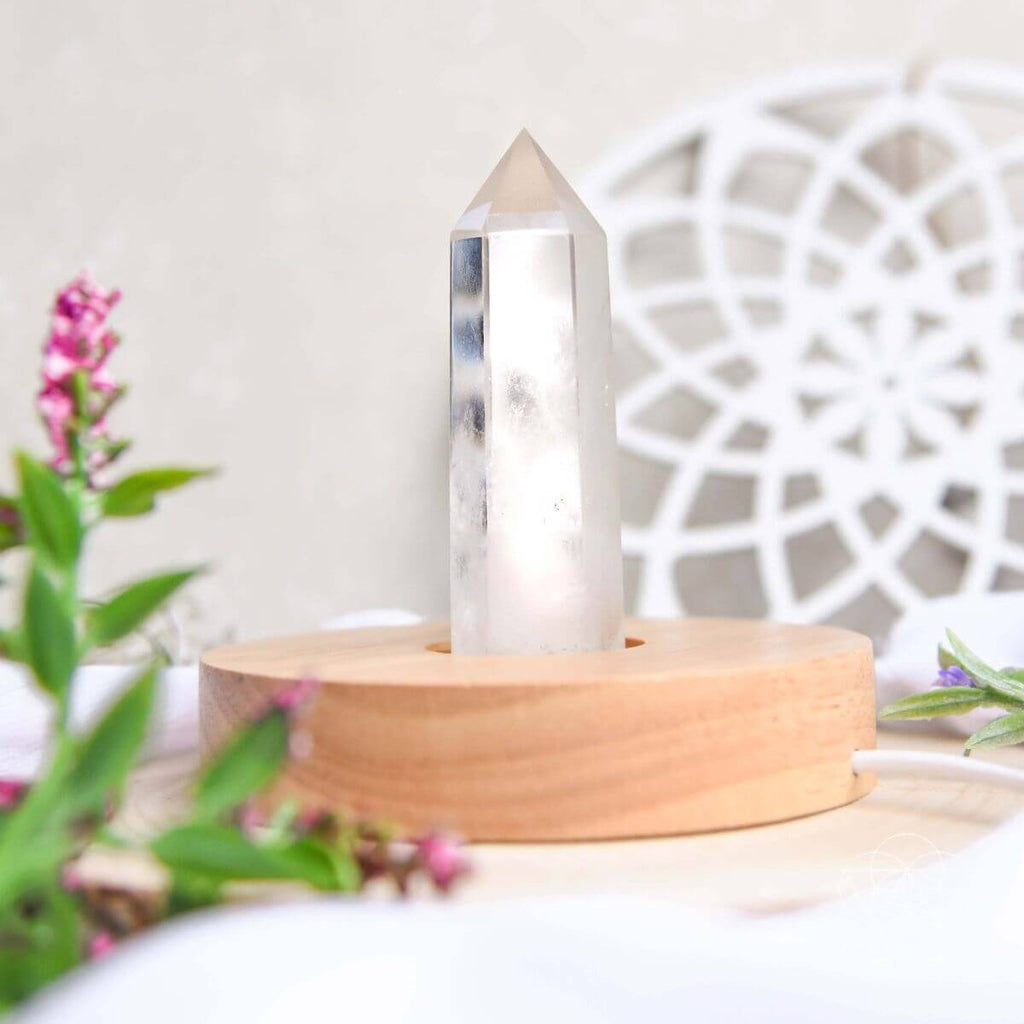 Clear crystal on a wooden stand with flowers and decorative elements in the background