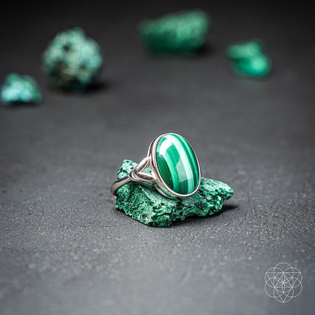 Green stone ring on a dark surface with green stones in the background