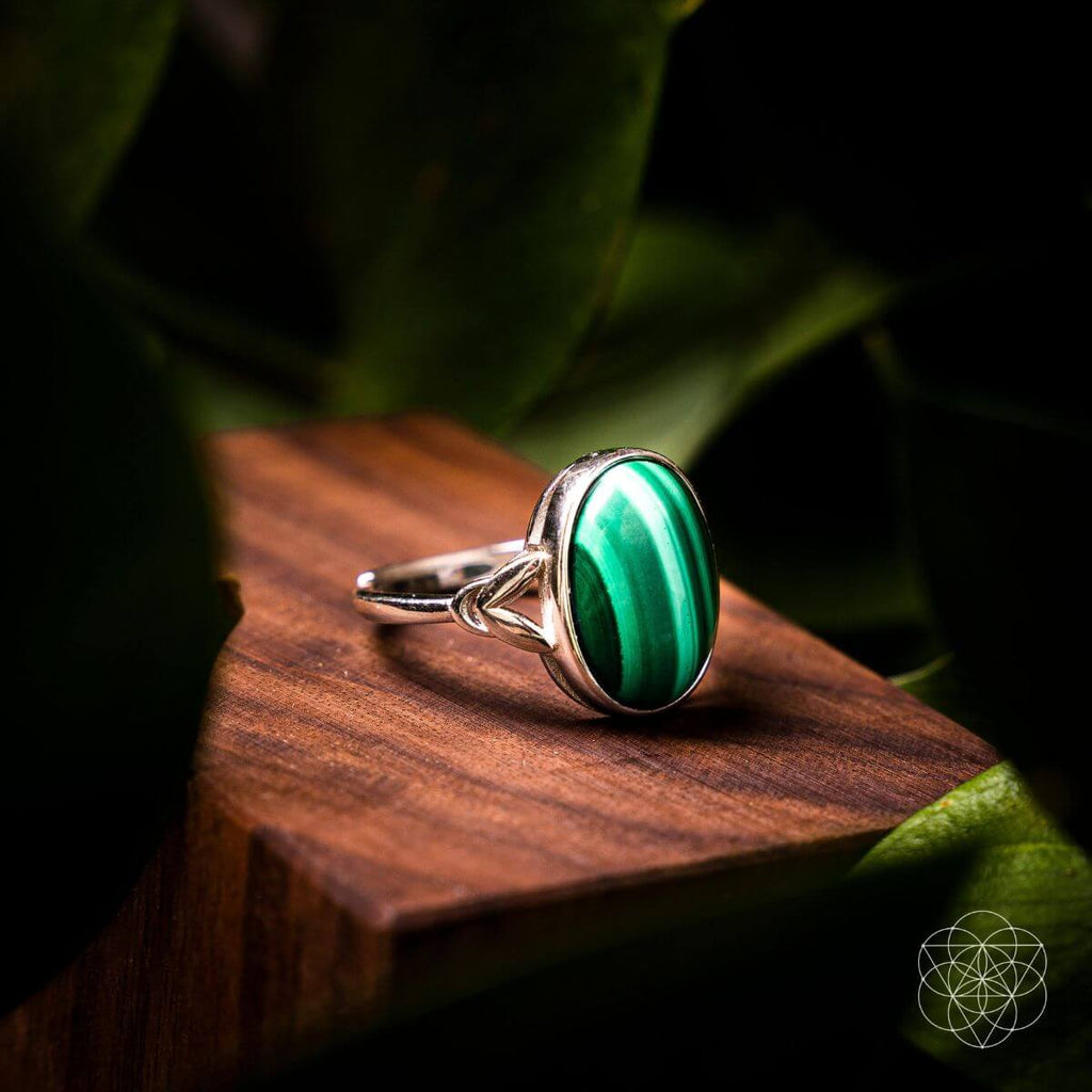 Silver ring with a green stone on a wooden surface with a natural background