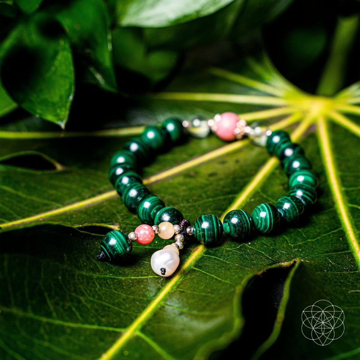 Beaded bracelet with green, pink, and white beads on a leaf