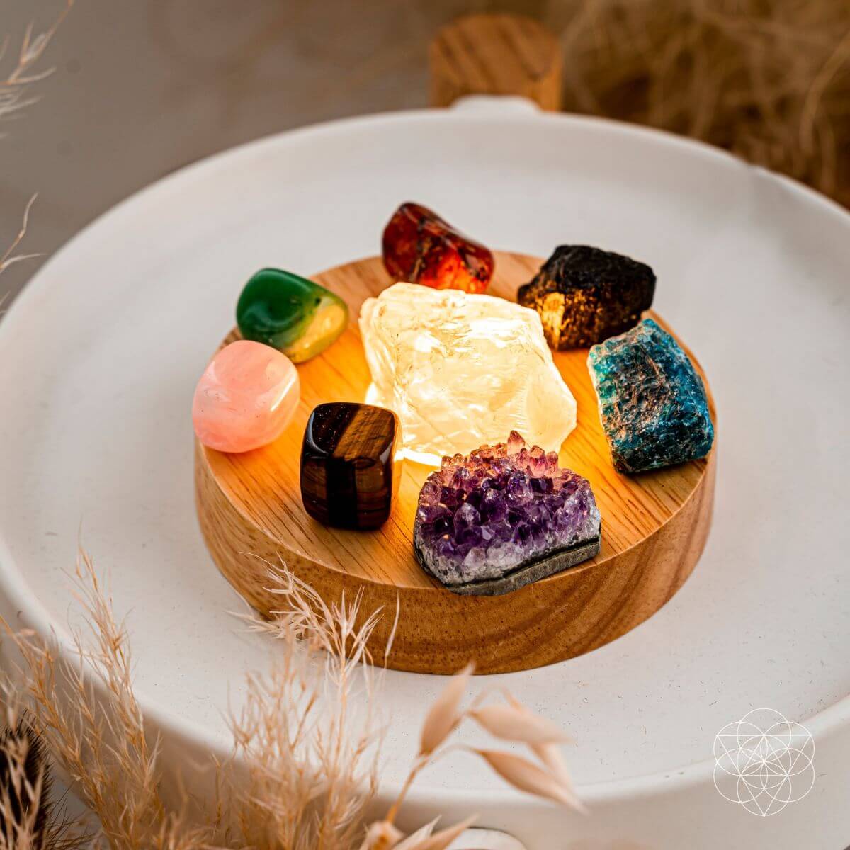 Set of colorful crystals on a wooden stand with a glowing crystal at the center, placed on a white surface.