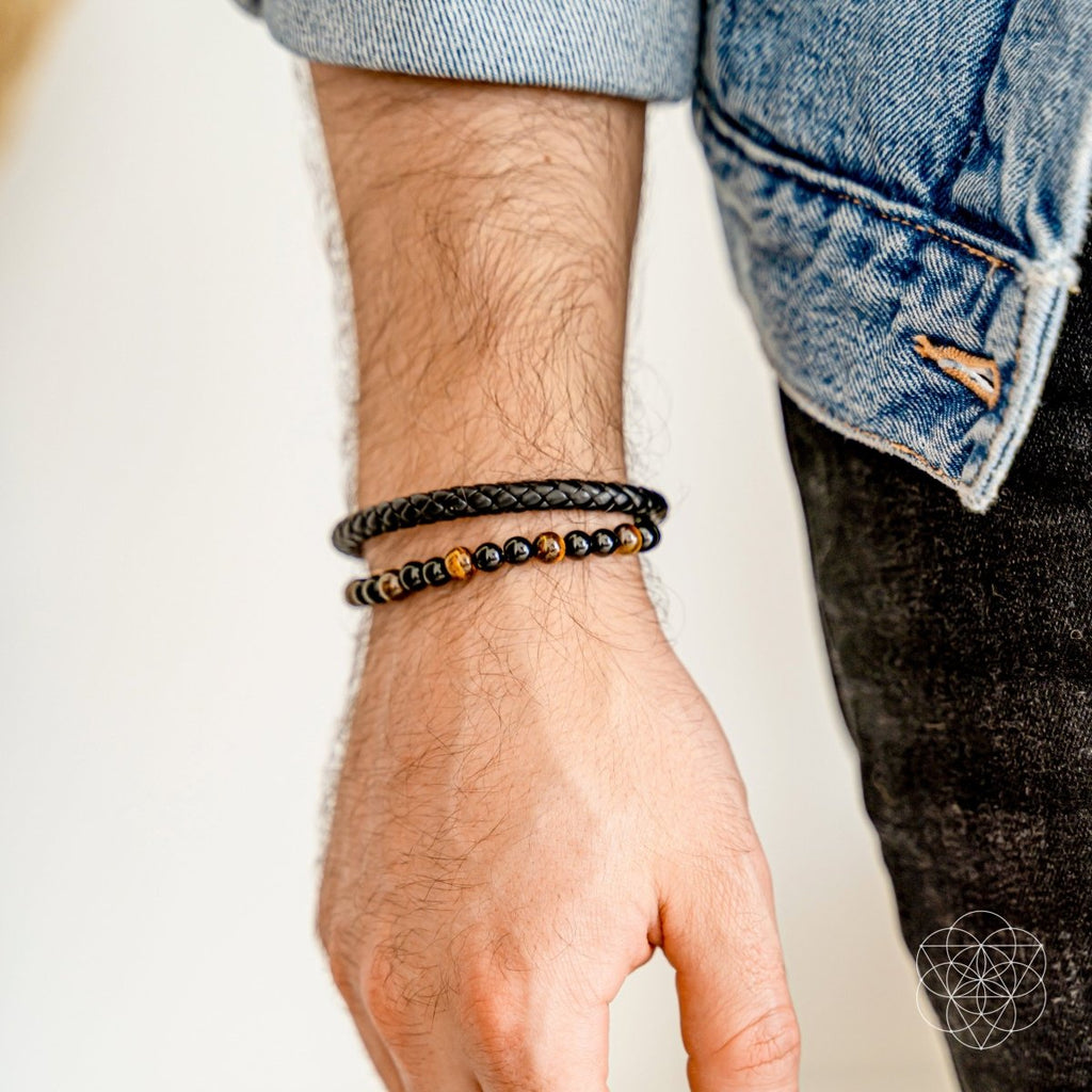 Hand wearing two beaded bracelets on a neutral background