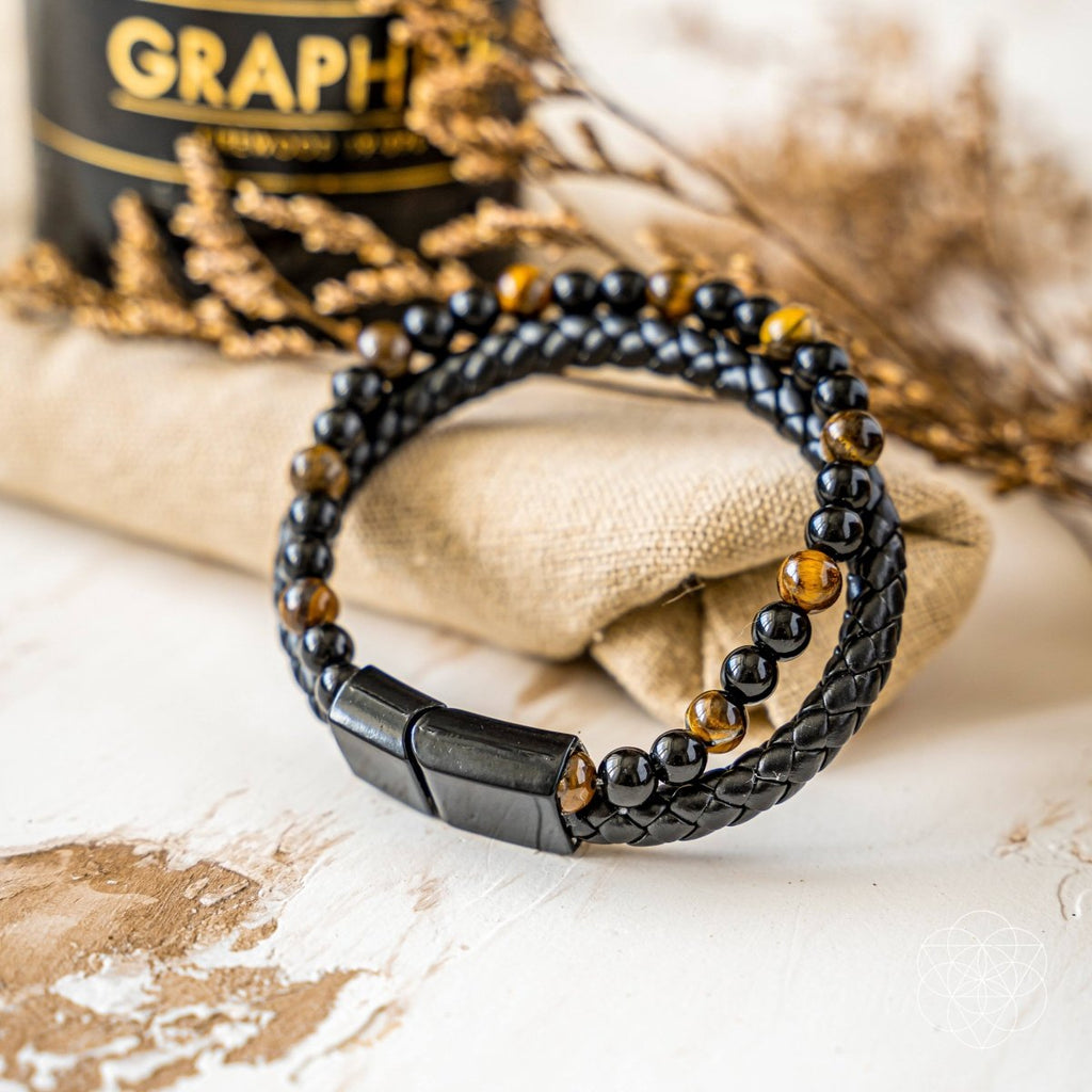Black beaded bracelet with a metallic clasp on a textured surface