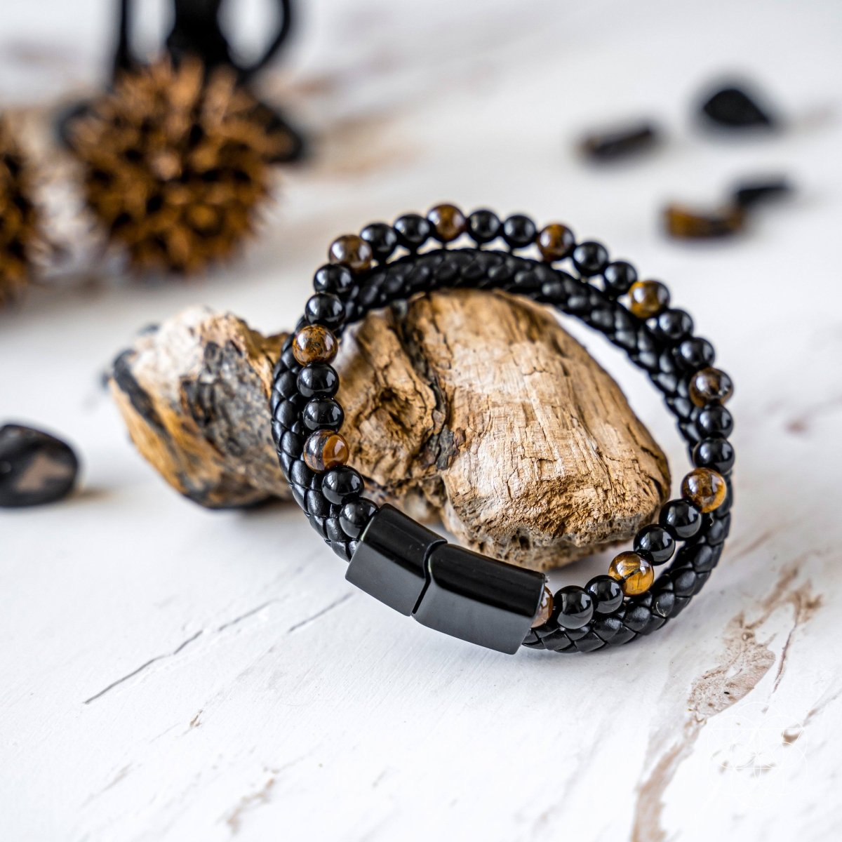 Black beaded bracelet with a magnetic clasp on a white surface with rocks and crystals.
