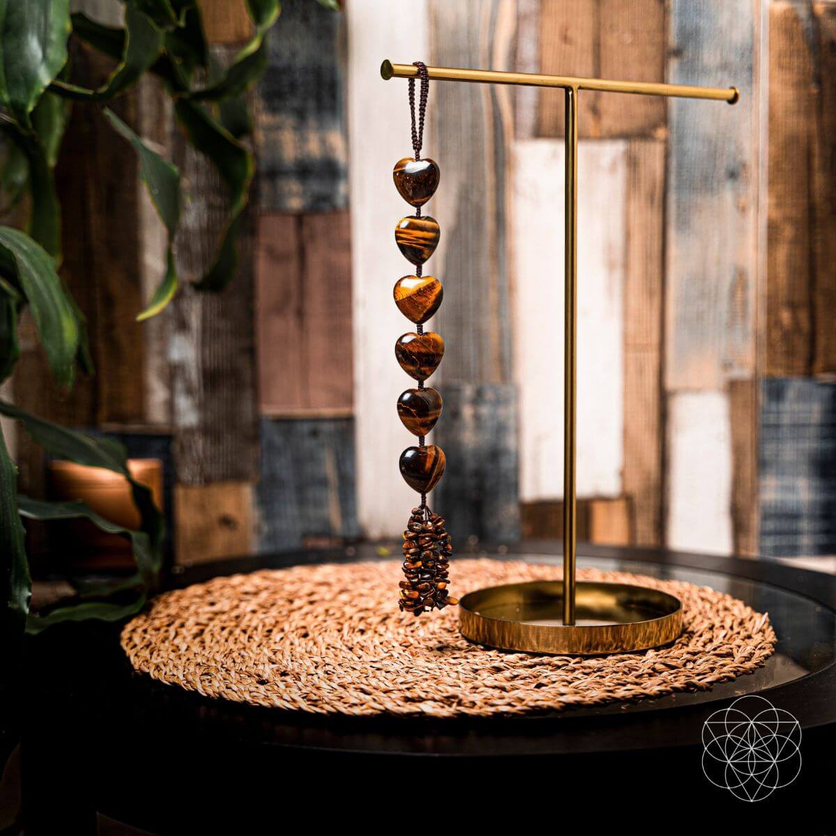 Decorative hanging beads on a gold stand with a woven mat and plant in the background