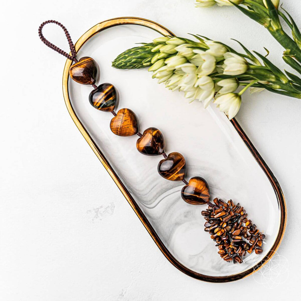 Tortoiseshell beaded necklace on a marble tray with white flowers and green leaves.