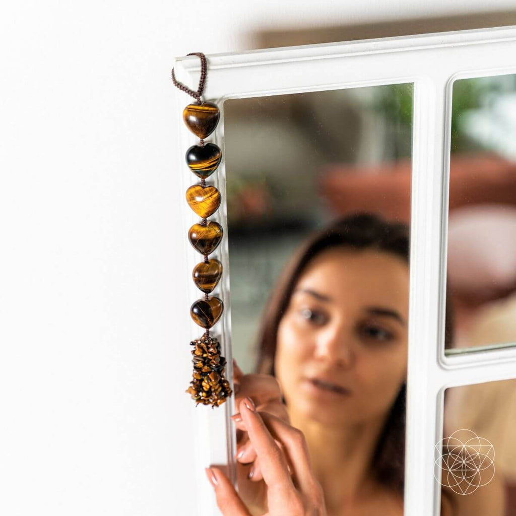 Woman holding a string of heart-shaped beads in front of a mirror