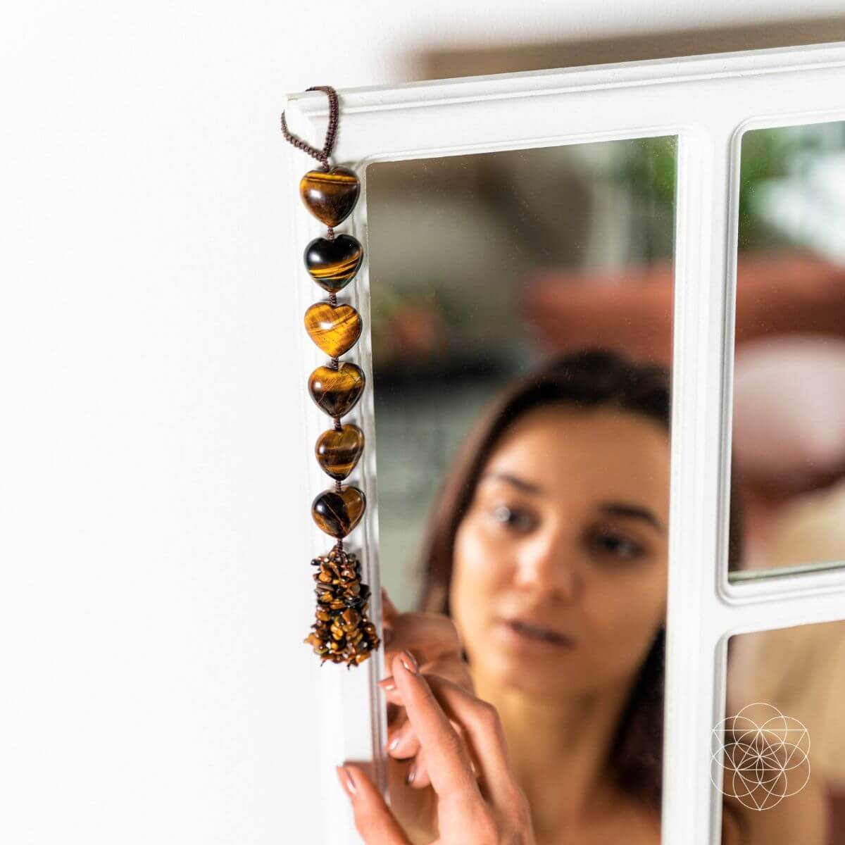 Woman holding a string of heart-shaped beads in front of a mirror