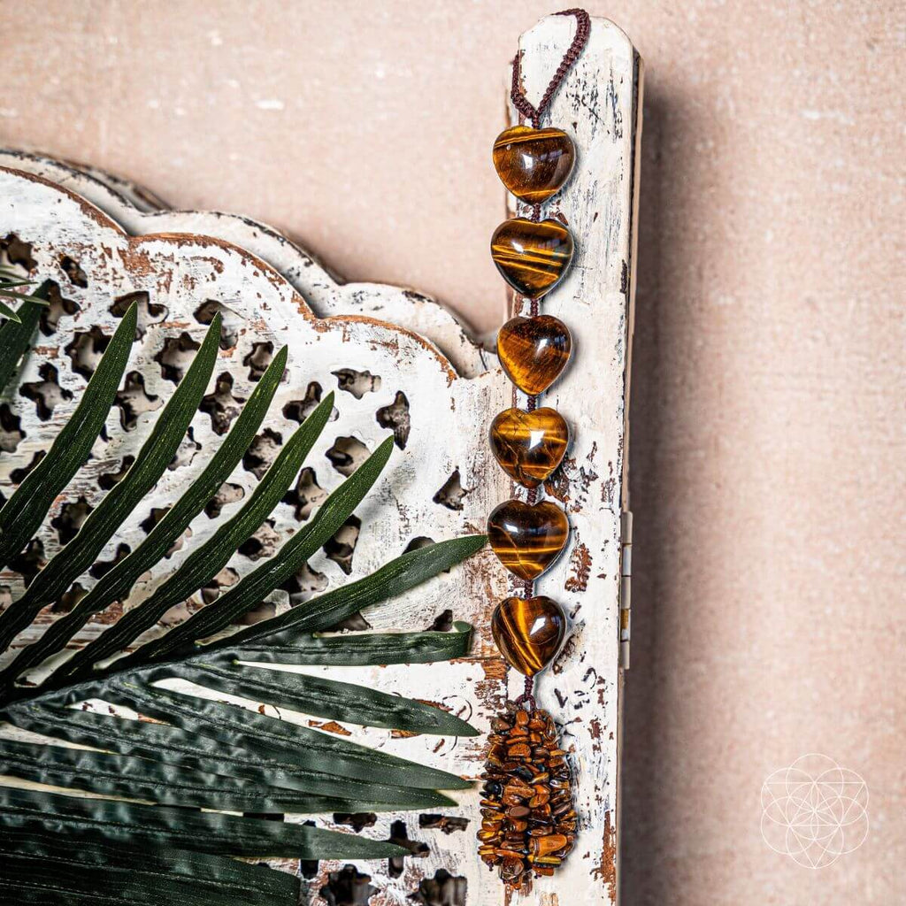 Decorative wall hanging with heart-shaped beads and a textured frame on a beige background