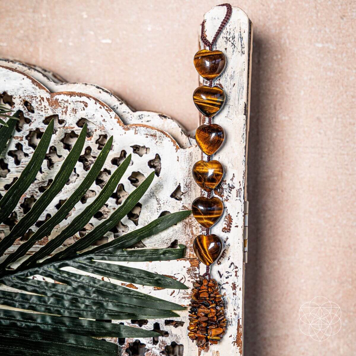 Decorative wall hanging with heart-shaped beads and a textured frame on a beige background