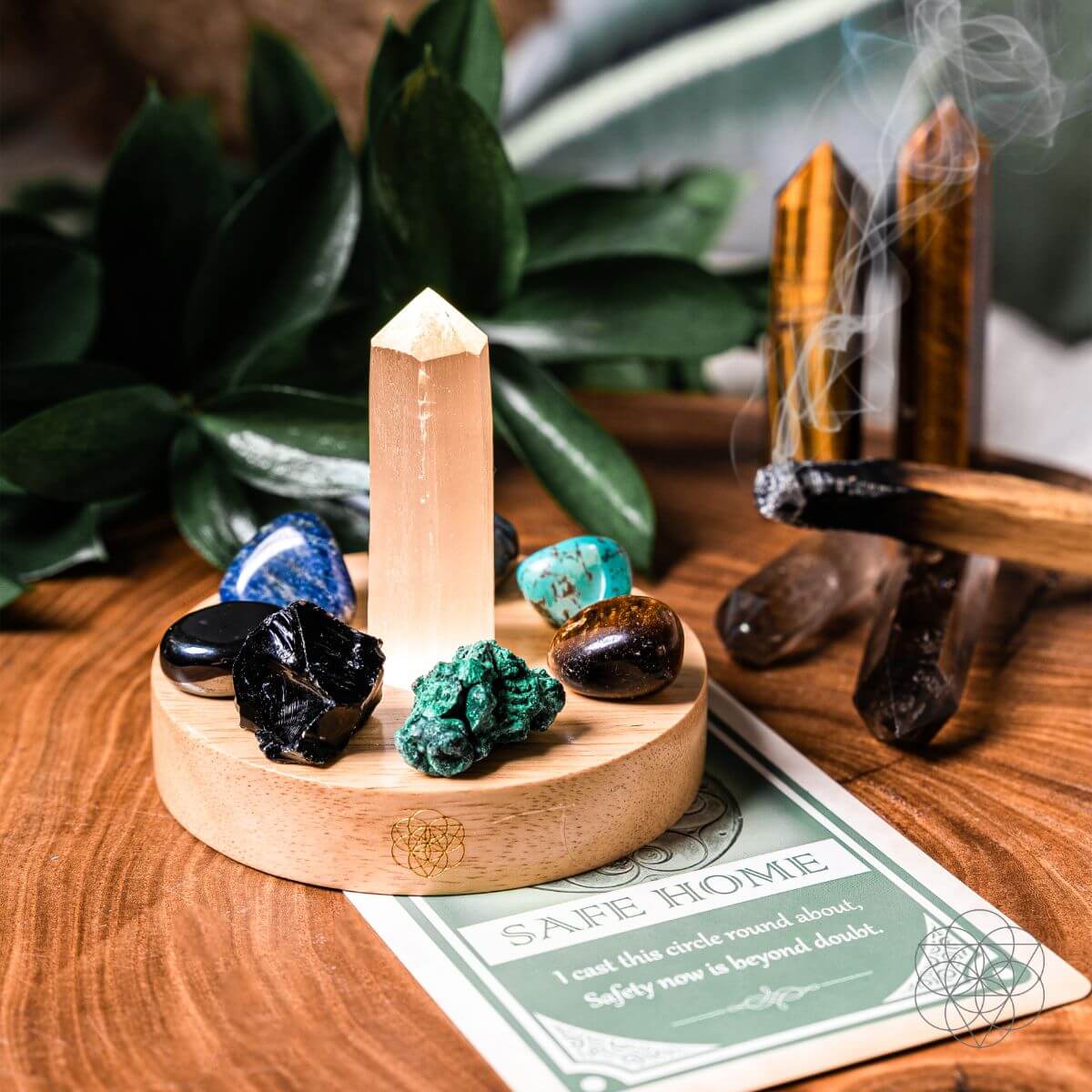 Crystal tower with stones and incense on a wooden surface with plants in the background