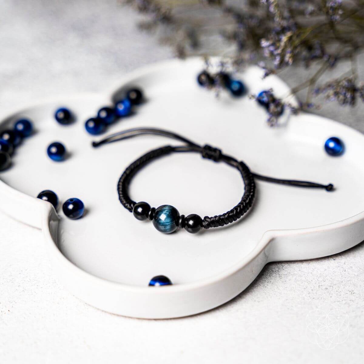 Black and blue beaded bracelets on a white decorative plate with a blurred background