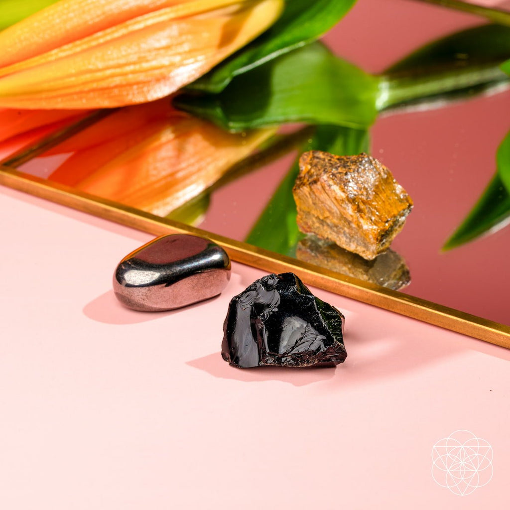 Mineral specimens on a reflective surface with a pink background
