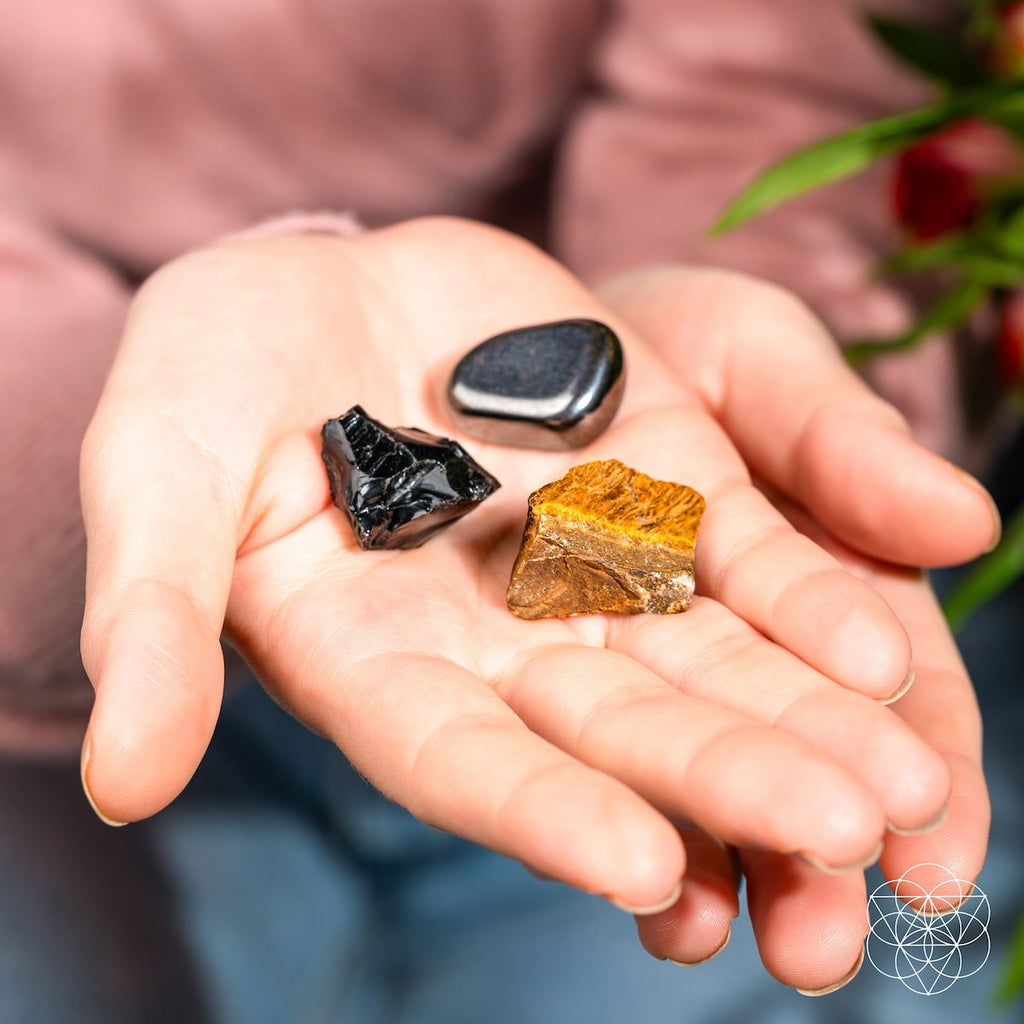 Three different colored stones held in a person's palm with a blurred background