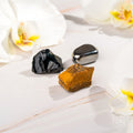 Three different colored stones on a light surface with flowers in the background